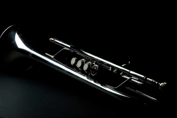 Close up of a shiny trumpet with detailed valves on a dark background