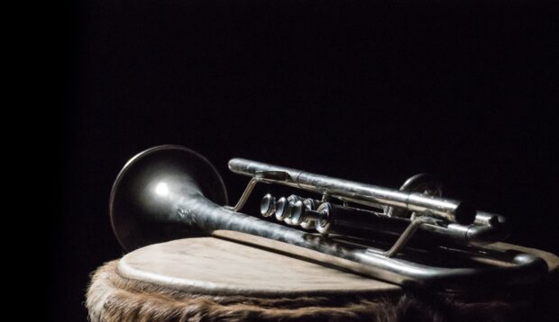 Vintage trumpet resting on a drum with a dark background showing the trumpet details