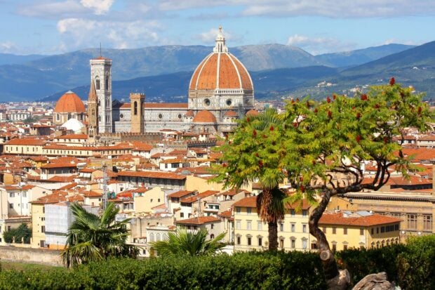 Historic architecture and green landscape of Tuscany with cathedral and hills in the background