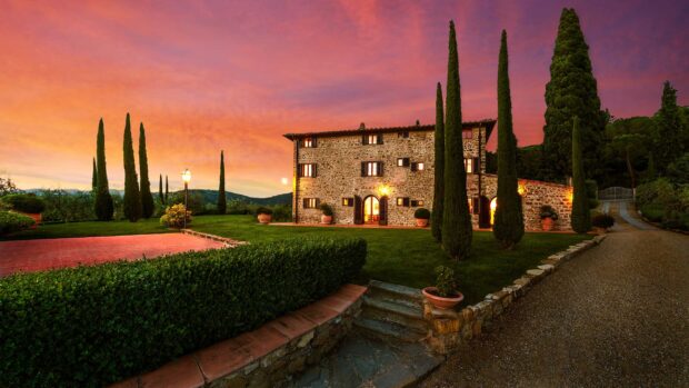 A beautiful Tuscany landscape with traditional stone house and tall cypress trees at sunset