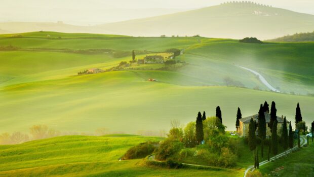 A peaceful Tuscany landscape with rolling green hills and traditional houses surrounded by cypress trees