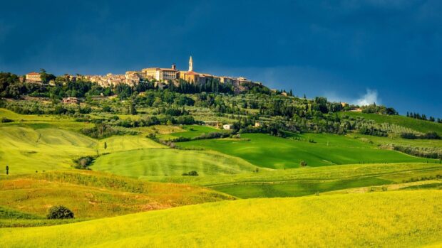 Rolling green hills and a hilltop village in Tuscany landscape