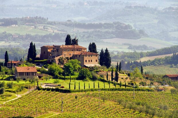 A scenic Tuscany landscape with vineyards and traditional Tuscan farmhouse surrounded by green hills