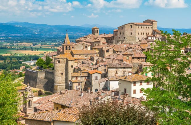A scenic view of Tuscany with historic buildings and rolling hills in the background