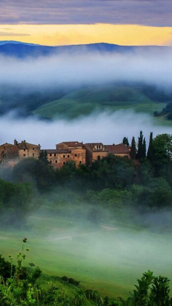 Misty hills and old Tuscan village landscape in the morning light