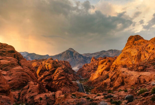 Red rock formations in the Usa desert with a road running through the valley under a cloudy sky