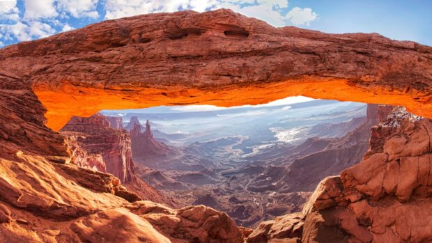 Natural rock formation in Utah with vast canyon landscape under a bright sky