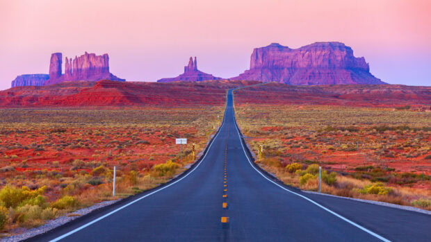 Scenic Usa desert road leading to red rock formations at sunset