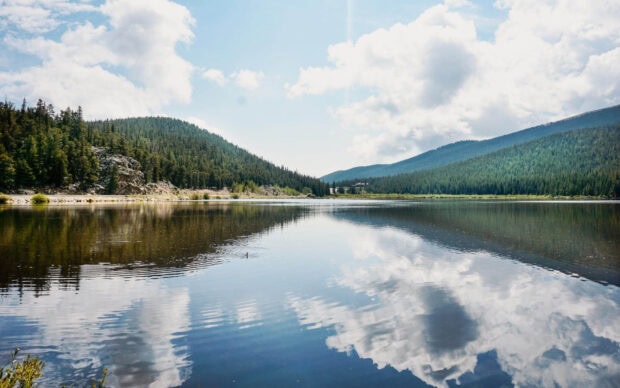 Calm lake surrounded by forested hills reflecting clouds in the Usa nature