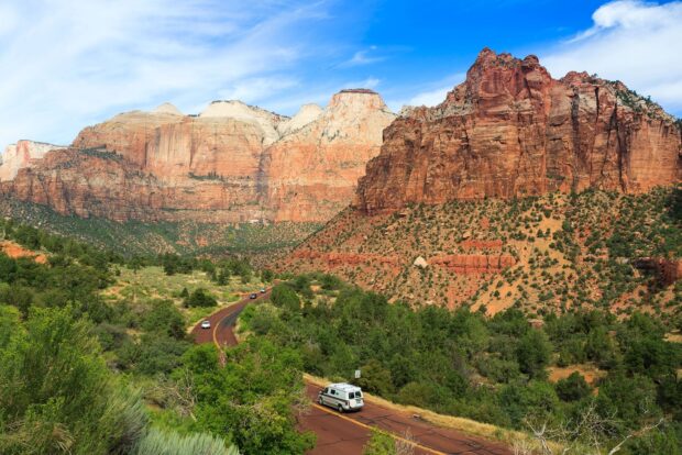 Scenic Utah landscape with rugged canyon cliffs and winding road through greenery