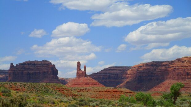Red rock formations and green desert vegetation under a blue sky in Utah