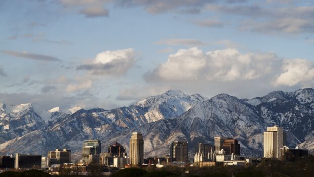 Snowy mountain range behind the Utah city skyline on a clear day with scattered clouds