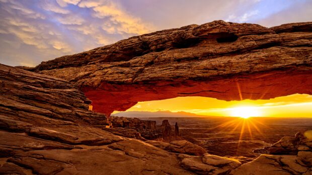 Natural rock formation in Utah with a sunlit desert landscape at sunset