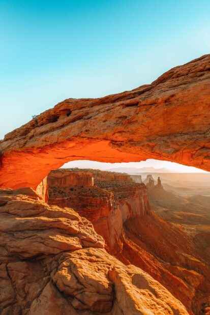 Natural rock arch formation in Utah desert landscape at sunrise