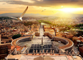 A bird flying over Vatican City in the golden sunlight with panoramic view
