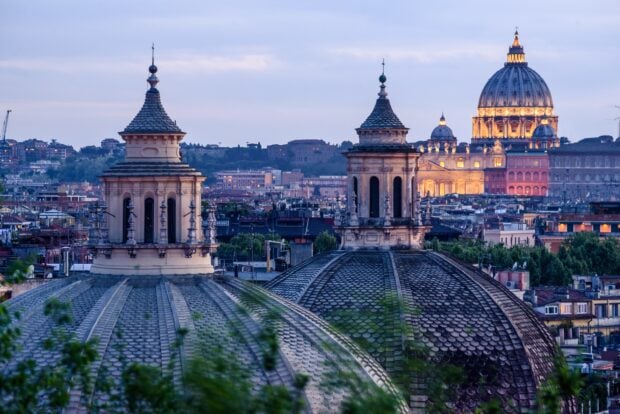 Domes and cityscape view of Vatican City at twilight with historical architecture