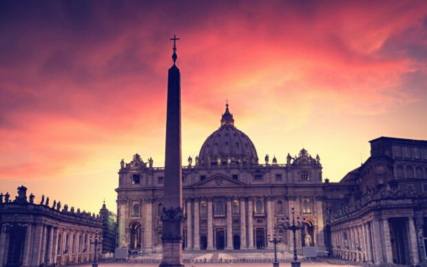 The iconic Vatican City dome and obelisk at sunset with a vibrant colorful sky