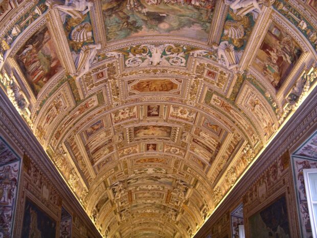 The intricate ceiling artwork inside Vatican City showcasing detailed frescoes and ornamental designs