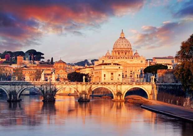 Stunning view of Vatican City with the famous dome and historic bridge at sunset