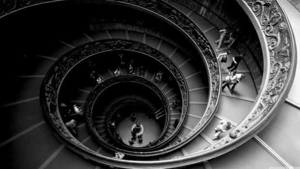 Spiral staircase with decorative railing in Vatican City filled with visitors