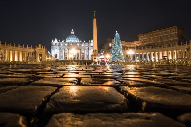 Vatican City square cobblestones illuminated at night showing historic architecture and Christmas tree
