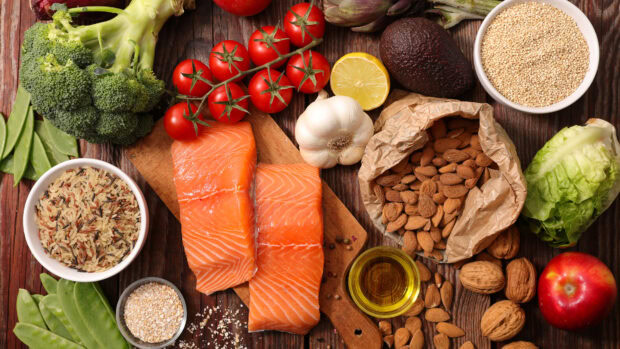 Fresh vegetables including broccoli cherry tomatoes and garlic on a rustic wooden board