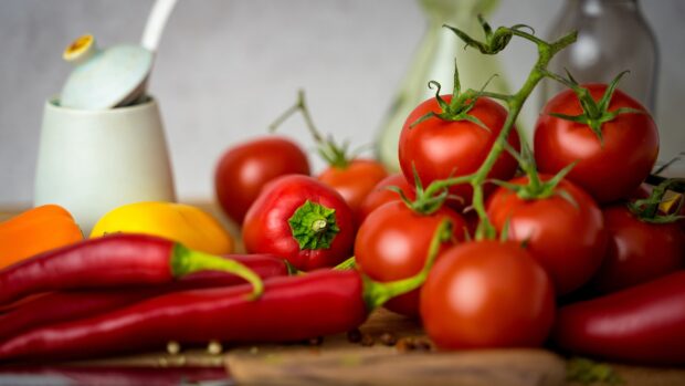 Fresh vegetables including tomatoes and chili peppers on a wooden surface