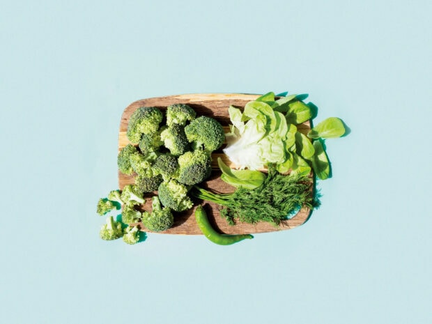 Fresh vegetables including broccoli lettuce dill and chili on a wooden board