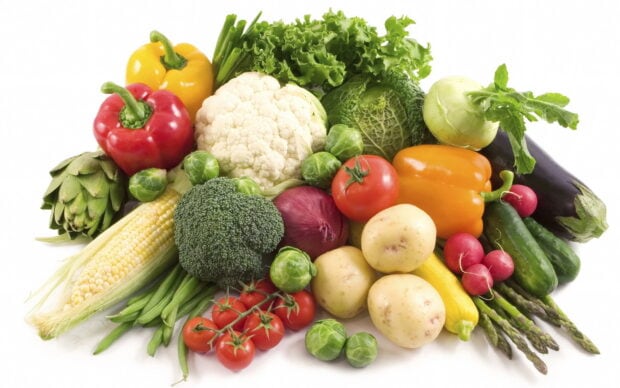 Fresh vegetables including broccoli tomatoes and potatoes arranged on a white background