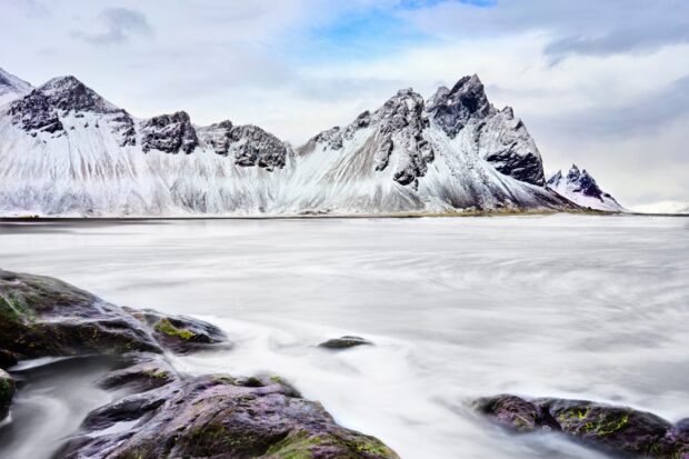 Snow covered sharp peaks of Vestrahorn Iceland with rocks in the foreground