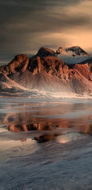 Sunrise over Vestrahorn Iceland mountain with reflection on icy shore