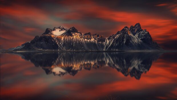 Vestrahorn Iceland mountain range reflected in calm water during sunset with dramatic sky