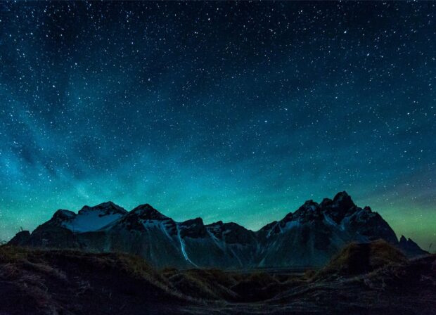 Snow capped Vestrahorn Iceland mountains under a starry night sky with northern lights visible