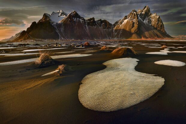 Black sand dunes contrast with snow patches near Vestrahorn Iceland