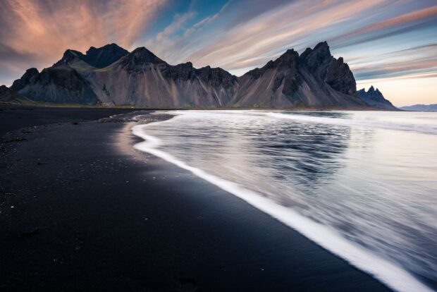 Majestic Vestrahorn Iceland mountain range with black sand beach and ocean waves at sunset