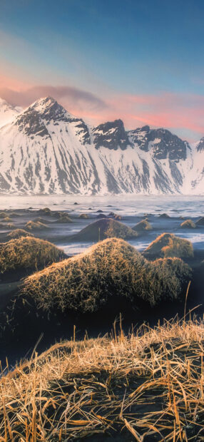 Snow covered mountains and grassy mounds in Vestrahorn Iceland