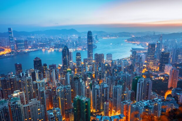 Victoria Peak cityscape at dusk with vibrant lights and harbor view in clear evening sky