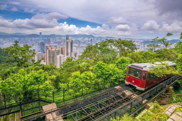 Victoria Peak railway ascending through lush greenery with a cityscape view in the background