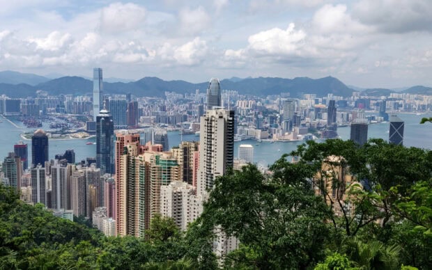 View of Victoria Peak skyline with high rise buildings and lush greenery in Hong Kong