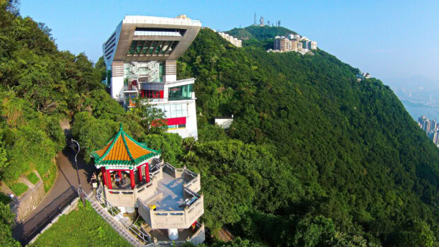 A scenic view of Victoria Peak with lush greenery and buildings on the hill