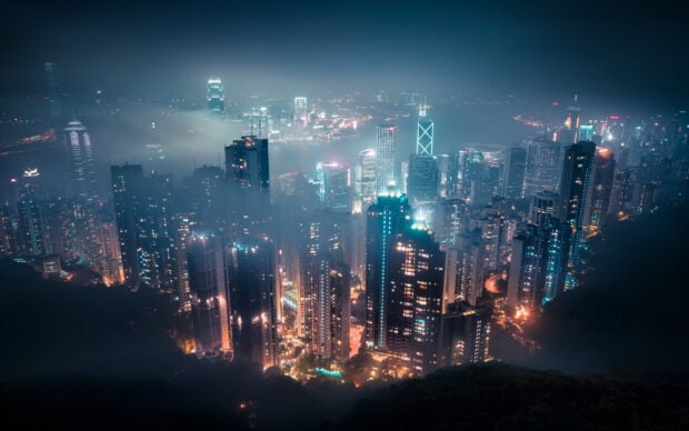A stunning view of Victoria Peak cityscape with high rise buildings and glowing lights at night