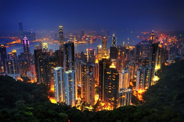 Evening cityscape of Victoria Peak with illuminated skyscrapers and lush greenery