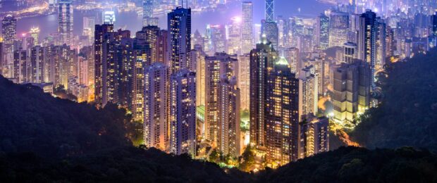 Nighttime cityscape of Victoria Peak with illuminated buildings and dense forest areas