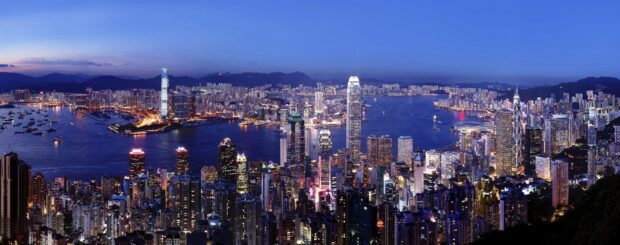 Stunning cityscape of Victoria Peak with high rise buildings and illuminated harbor at dusk
