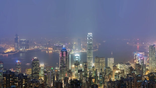 Night view of Victoria Peak cityscape with illuminated buildings and harbor lights