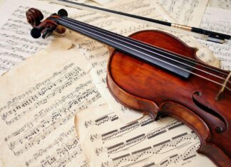 A wooden viola resting on old sheet music showcasing classic musical notes and vintage pages