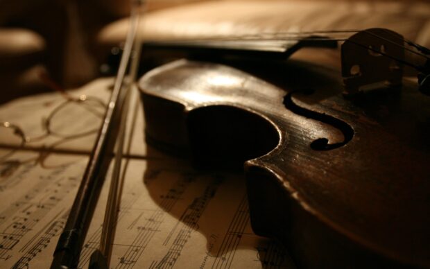 Close up of a viola resting on sheet music in warm soft lighting
