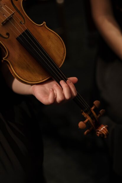 Close up of hand holding the viola neck in a dark setting