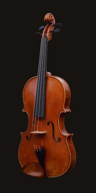A close up view of a violin viola showing the wooden body and strings against a black background