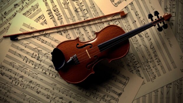 A wooden viola resting on classical music sheets in a warm lit setting